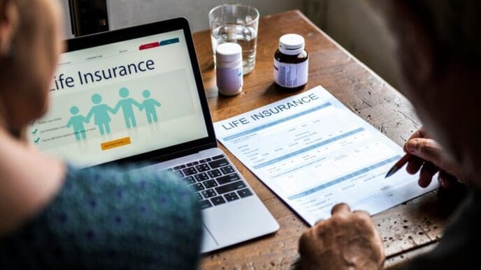 An elderly couple reviews documents together, presumably planning their life insurance.