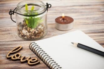 A blank notebook lies open next to a wooden sign that reads "Love."