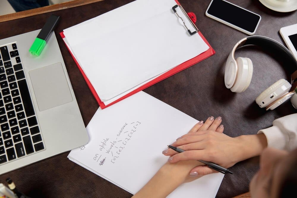 Close-up of a teacher and student's hands interacting during an English lesson in an interior setting.