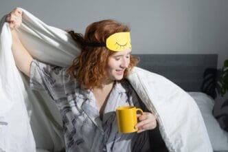Person wearing a sleep mask and holding a mug, likely enjoying coffee during a morning routine.