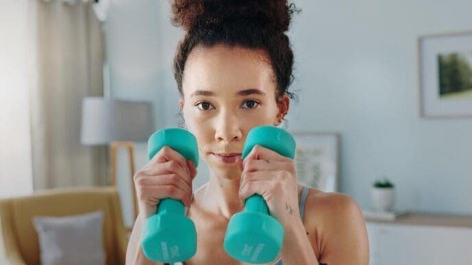 A woman boxes and watches a tablet for an online aerobics tutorial at home.