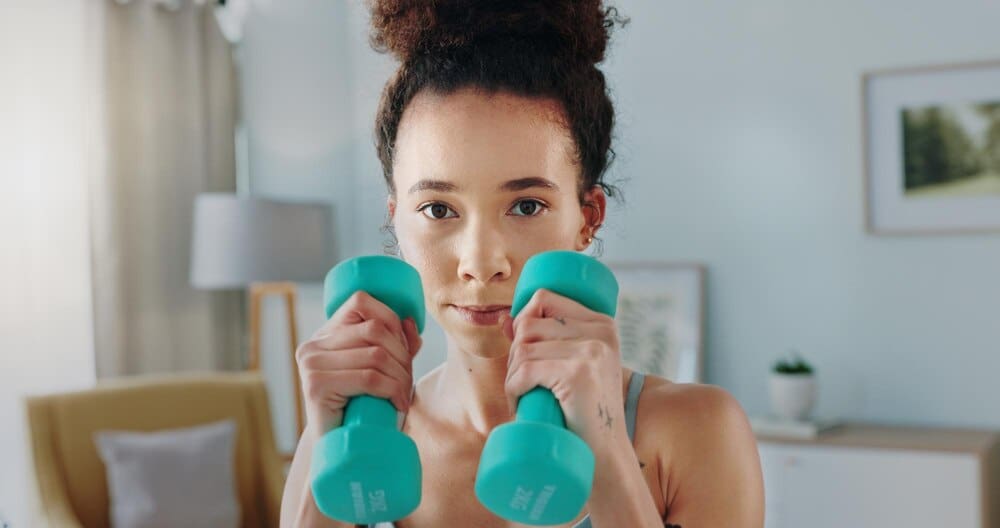 A woman boxes and watches a tablet for an online aerobics tutorial at home.