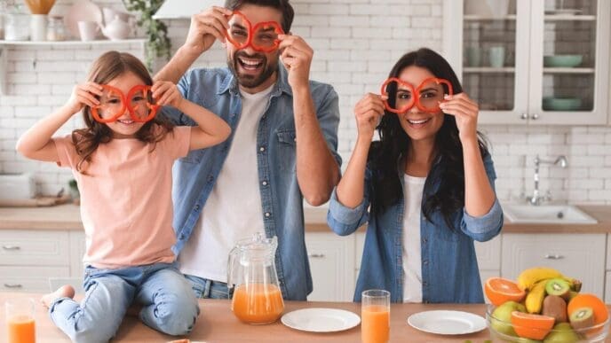 A family holds bell pepper rings over their eyes and smiles at the camera.