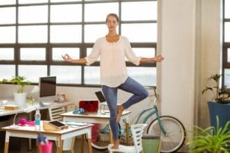 A woman in business attire performs a yoga pose.