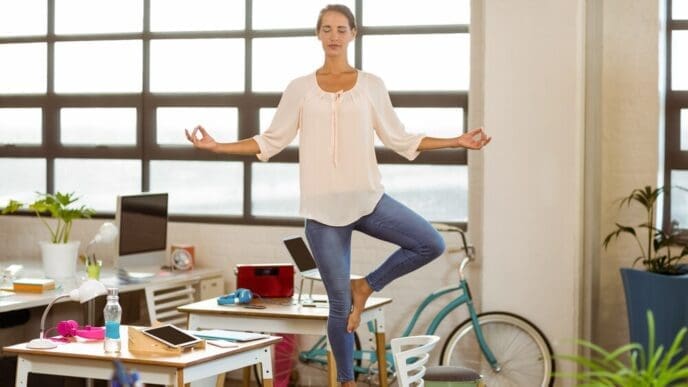 A woman in business attire performs a yoga pose.