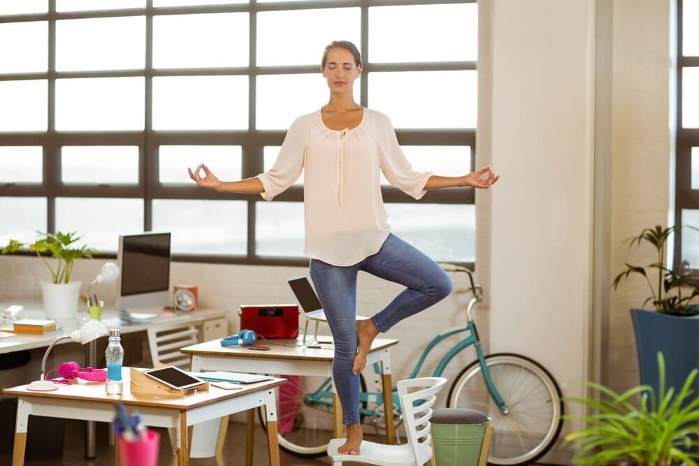 A woman in business attire performs a yoga pose.