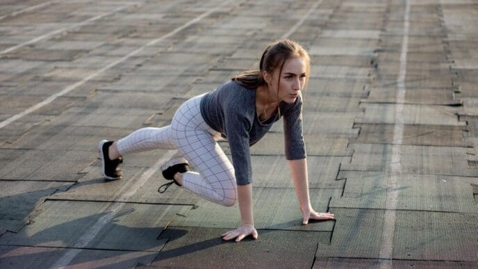 A female runner stretches her legs on a running track.