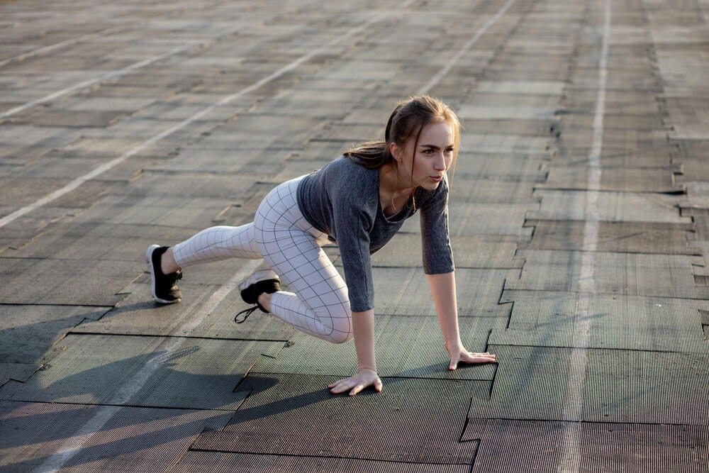 A female runner stretches her legs on a running track.