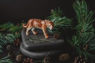 A figurine of a tiger, a symbol of the 2022 Chinese New Year, is surrounded by pine branches and cones.