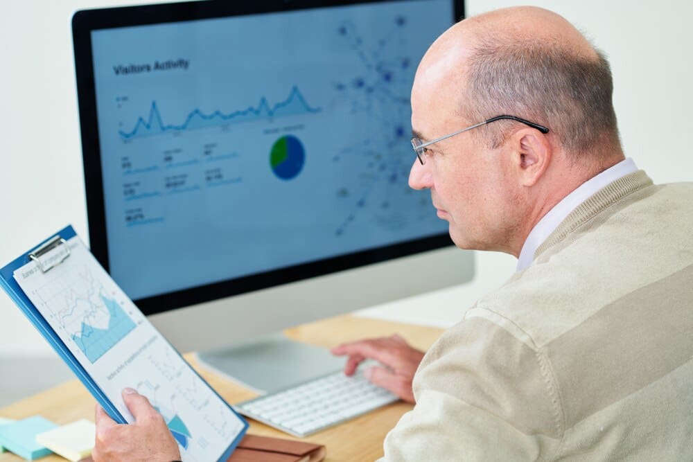 A financial analyst reviews reports while working at a desk.