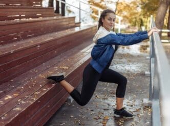 A slim woman stretches her legs outdoors, promoting a healthy lifestyle.