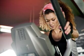 A woman uses a stepper machine for a cardio workout in a fitness gym.