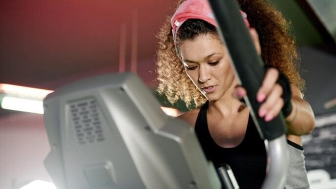 A woman uses a stepper machine for a cardio workout in a fitness gym.