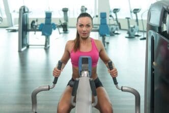 A woman uses a weight machine to perform a back exercise.