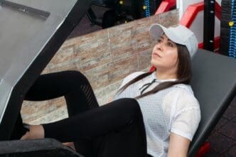 A woman uses a weight machine to do a leg exercise in a gym.