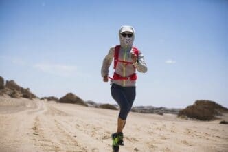 Woman trail running across a desert landscape.