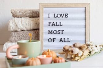 A flat lay features a felt letter board with the text "I love fall most of all" surrounded by autumn-themed decorations.
