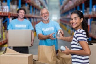 A smiling woman hands bags of goods to a group of volunteers.