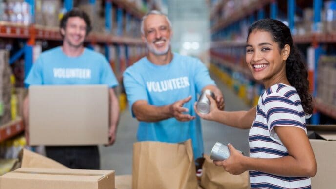 A smiling woman hands bags of goods to a group of volunteers.