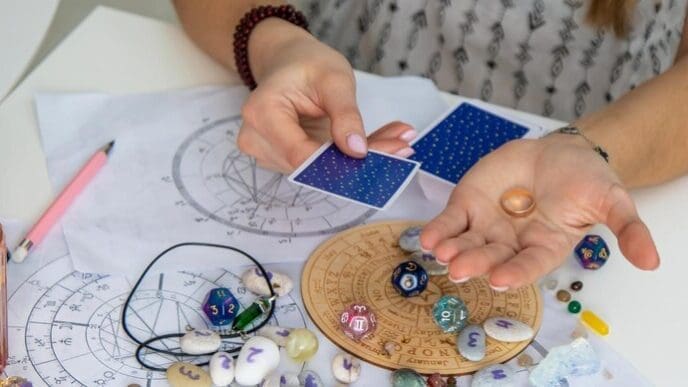 A fortune teller wearing a headscarf and holding tarot cards is seen in selective focus.