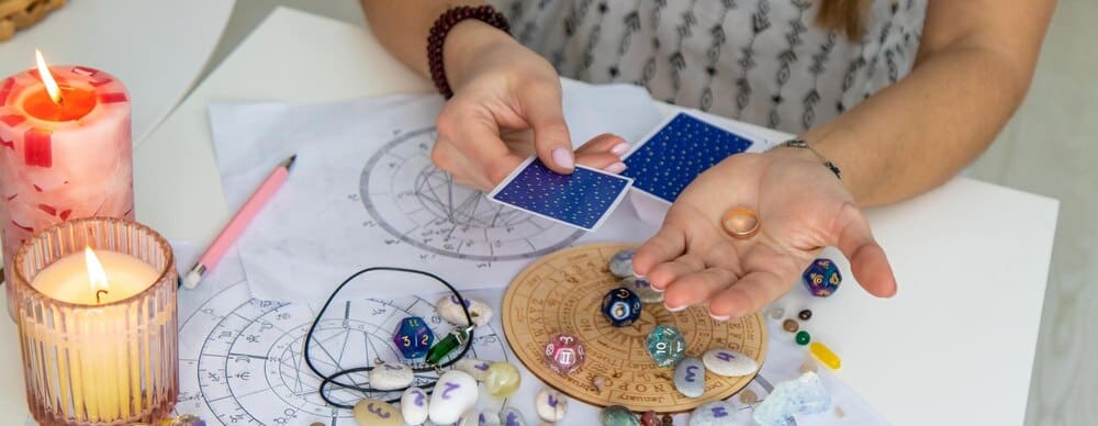 A fortune teller wearing a headscarf and holding tarot cards is seen in selective focus.