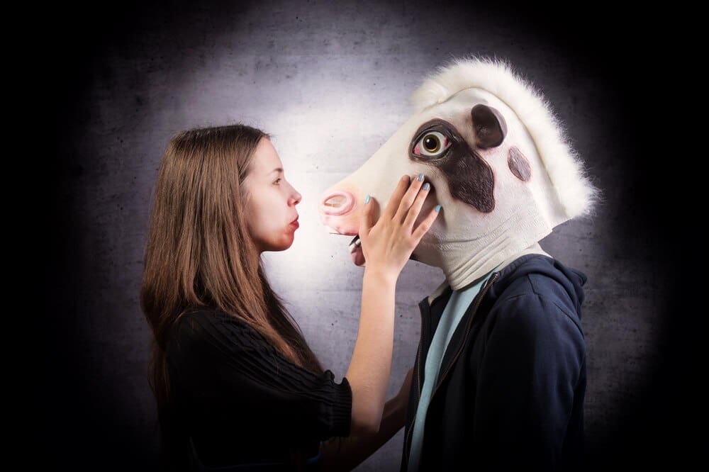 A girl and a boy stand close together, each wearing a horse head mask, creating a surreal and unusual image.