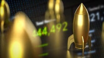 A golden rocket model sits on a blurred background with business-related graphics.