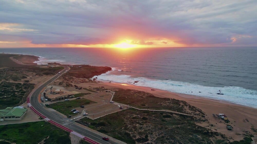 Aerial view of the ocean surface at sunrise, with golden sunlight reflecting on the water.