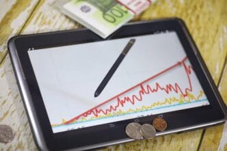 A tablet and smartphone display a line graph illustrating income growth, likely with currency symbols indicating profit.
