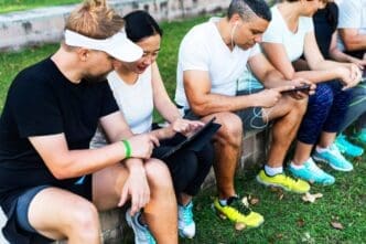 A diverse group of people uses various digital devices, such as phones and laptops.
