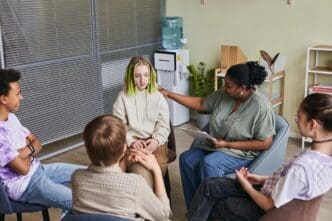 Group of teenagers sitting in a circle, sharing their problems with a psychologist who is listening attentively.