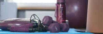 Close-up of various pieces of gym equipment, such as weights and exercise bands, arranged for a home workout.