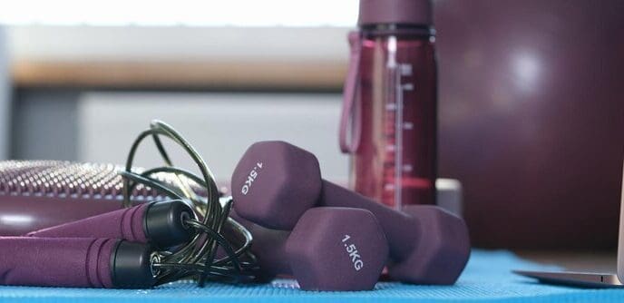 Close-up of various pieces of gym equipment, such as weights and exercise bands, arranged for a home workout.