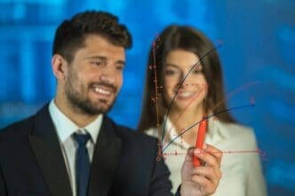 A man and a woman smile as they draw together on a digital whiteboard.