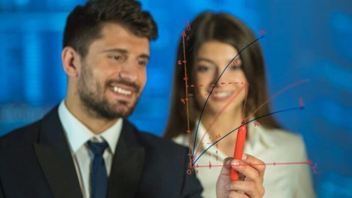 A man and a woman smile as they draw together on a digital whiteboard.