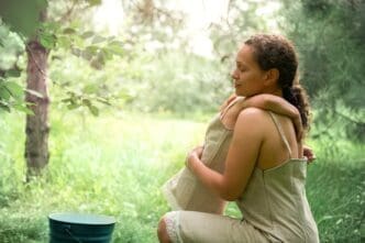 A mother and daughter in linen dresses share a hug in a cherry orchard, bathed in sunlight.