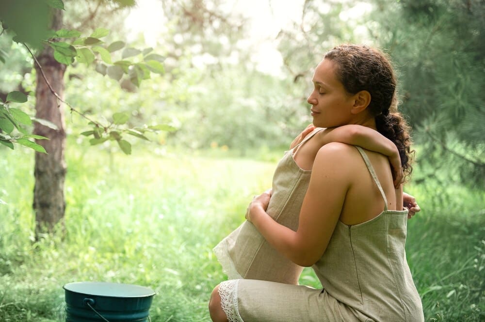 A mother and daughter in linen dresses share a hug in a cherry orchard, bathed in sunlight.