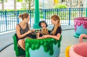 A mother and son ride a carousel together, smiling and enjoying themselves at an amusement park.
