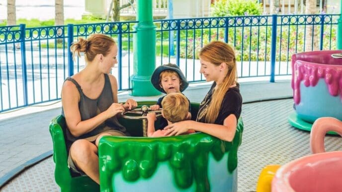 A mother and son ride a carousel together, smiling and enjoying themselves at an amusement park.