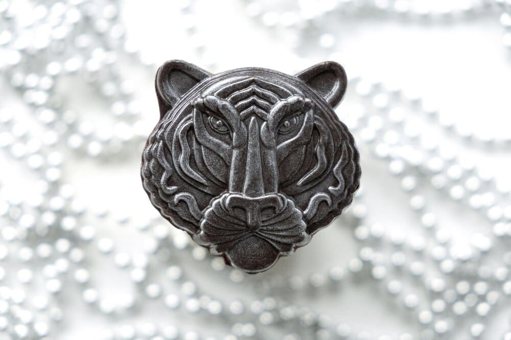 A chocolate tiger figure, representing the Chinese New Year, is set against a gray background with soft lights.