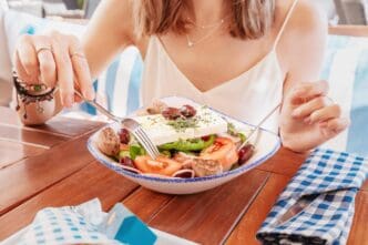 A smiling woman enjoys a Greek salad Horiatiki in a restaurant.