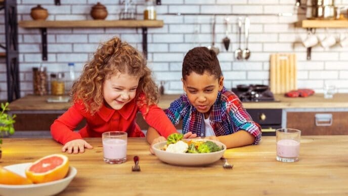 A frustrated young girl pushes away a bowl of broccoli.