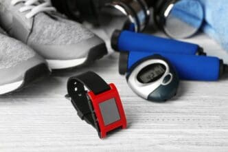 A smartwatch and other fitness equipment are arranged on a light-colored wooden surface.