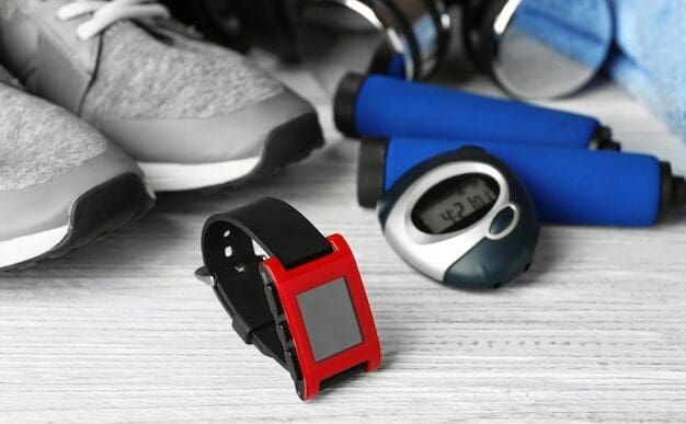 A smartwatch and other fitness equipment are arranged on a light-colored wooden surface.