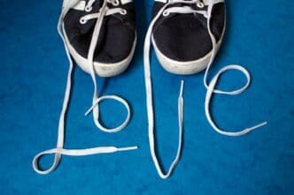 A high-angle shot shows the word "love" spelled out on a wooden floor using red shoelaces.