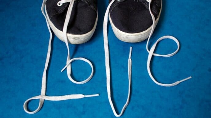 A high-angle shot shows the word "love" spelled out on a wooden floor using red shoelaces.