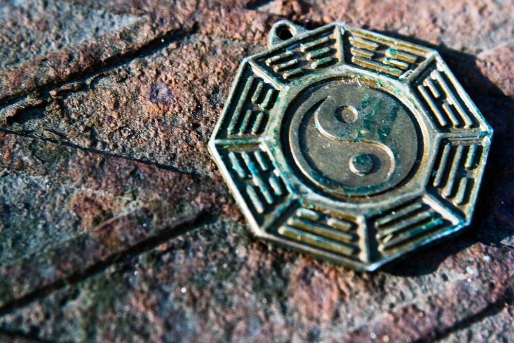 A metal pendant rests on a textured rock, viewed from above.