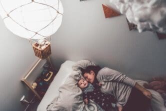 High-angle shot shows a mother and son lying on a bed together in a home setting.