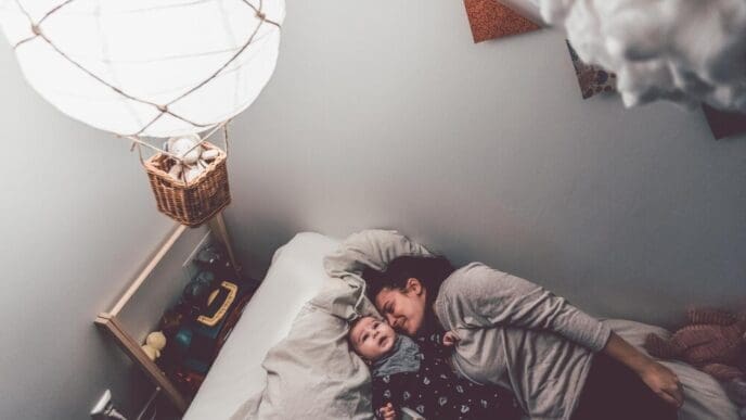 High-angle shot shows a mother and son lying on a bed together in a home setting.