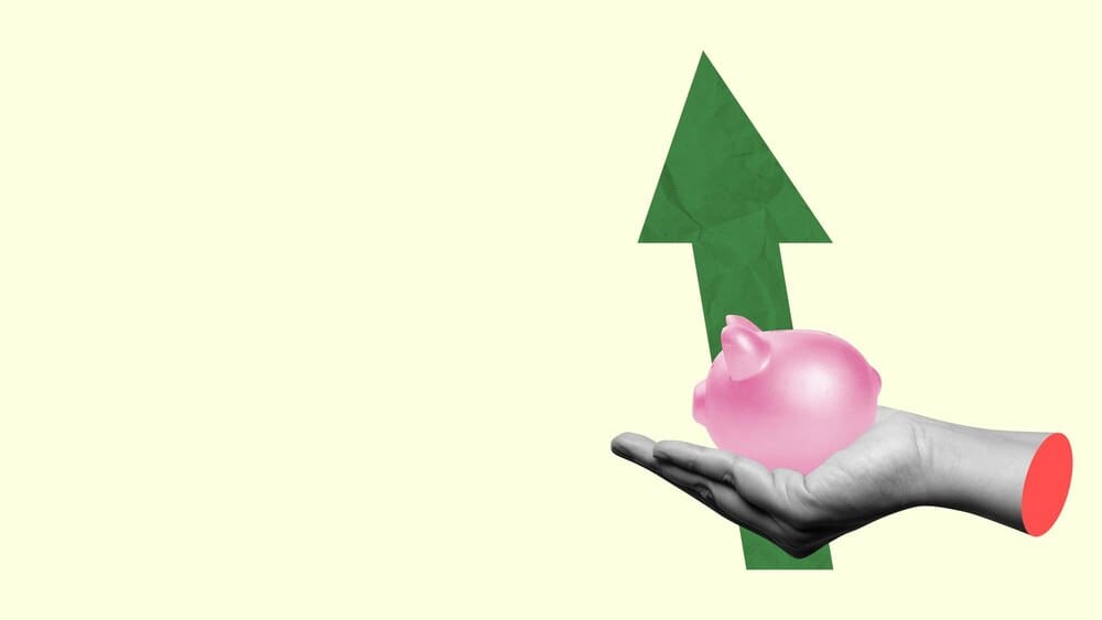 A hand holds a piggy bank, with an upward-pointing arrow graph superimposed.